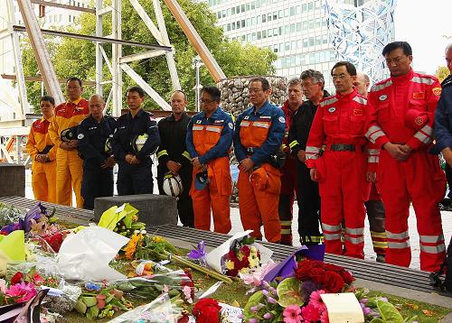 3月1日,两名中国救援队队员(红衣)与各国救援队员一起在新西兰克赖斯特彻奇市中心大教堂前为地震死难者默哀。新西兰全国各地的民众以及正在当地的各国救援队员于当地时间1日中午12时51分默哀两分钟,哀悼地震中的遇难者。新华社发