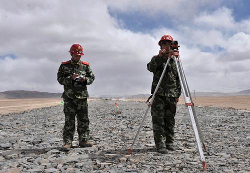 在新藏公路新疆段高原冻土层测绘的武警战士(5月2日摄)。在翻越新疆奇台达坂后,新藏公路(国道G219)进入新疆段海拔最高的部分,平均海拔接近5000米。武警交通二总队第八支队的官兵们将在此担负起新藏公路新疆段第七标段的建设任务。这里高寒缺氧,年平均气温在零下5度左右;另外,超过120公里地质结构复杂的高原冻土层,以及年平均超过100天的大风天气,增加了施工的难度。新华社记者 江文耀 摄