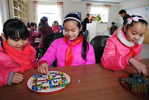 1月16日,重庆市九龙坡区西彭镇第三小学的赵艺(中)与同学在东林村“留守儿童幸福家园”下跳棋。新华社记者 李健 摄