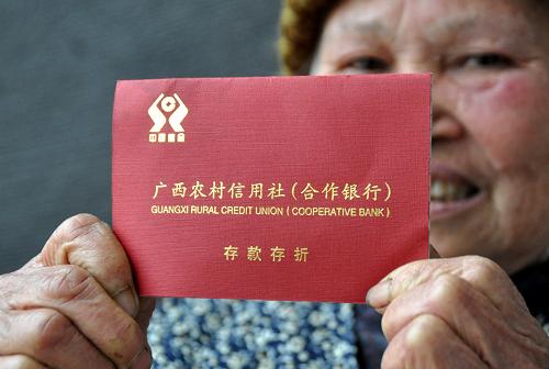 2月27日,在广西南宁市兴宁区五塘镇社会保障服务中心,一名老人在展示刚刚领到的专门存取新型农村社会养老保险金的存折。从2012年1月1日起,广西实施新型农村社会养老保险制度全覆盖工作,逐步解决全区适龄农民老有所养问题。坚持政府和个人共担责任,政府对无力承担个人责任的困难群众代为缴费,帮助其参保。截至2011年底,广西新农保和城镇居民社会养老保险试点覆盖面分别达到68%和66%,共有878.93万人参保,322.68万人领取了养老金,共发放养老金14.66亿元,基金累计结余16.81亿元。新华社记者 陆波岸 摄