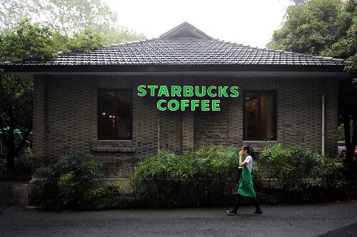 9月22日,一名店员从星巴克灵隐寺店前走过。星巴克,代表着美国典型的咖啡文化;灵隐寺,则承载着中国千年佛教文化。当日,当星巴克“入驻”杭州灵隐景区的消息一出,社会上一片沸腾,因为当星巴克“遭遇”灵隐寺,触痛的是国人对于我国一些名胜古迹过度商业开发敏感的神经。 新华社记者 鞠焕宗 摄