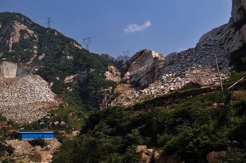 位于陕西华山以西12公里处的大夫峪内,原本巍峨青翠的秦岭山脉上,一片片支离破碎的灰白山体在周围山峰的映衬下格外刺目。从2007年开始,数十家采石场陆续进驻开山采石,开采落下的大量碎石、泥土都废弃在山上或者落入河道,一遇大雨,河道堵塞,造成各种险情。2010年7月,秦岭山洪引发泥石流,无法疏通的河道给当地居民带来严重危害。开采花岗岩对当地自然生态景观造成的破坏令人担忧,秦岭上一块块秃山被当地人戏称为“牛皮癣”。关中城市群的天然生态屏障、承担我国南水北调中线工程水源地保护重要作用的秦岭,该如何承受“新妆”之重?大夫峪内两座相对的山体被采石场开采(2012年7月10日摄)。新华社记者 刘潇 摄