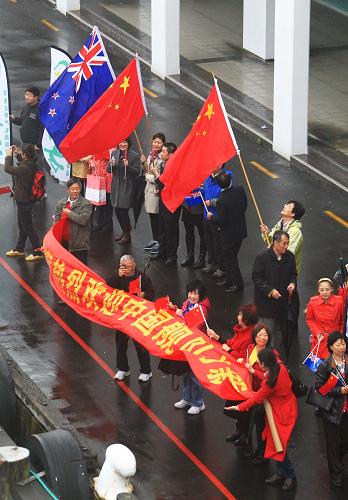 10月11日,新西兰华人华侨挥舞五星红旗在奥克兰港码头迎接从祖国来的军舰。新华社记者 查春明 摄
