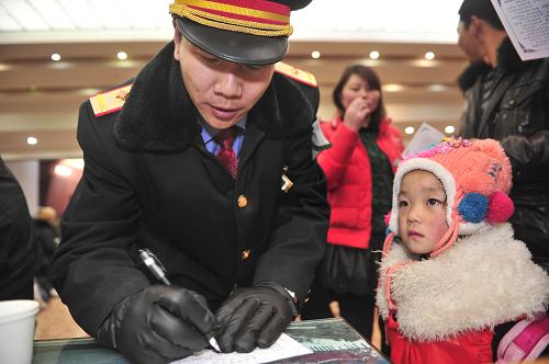 1月16日,在西藏拉萨火车站,火车站工作人员在为准备上车的乘客填写健康表。新华社记者 刘坤 摄