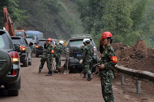4月22日,雅安震区余震频发,武警水电三总队官兵在危情路段设立道路安全员疏导车辆、安全警戒。新华社发(刘海山 摄)