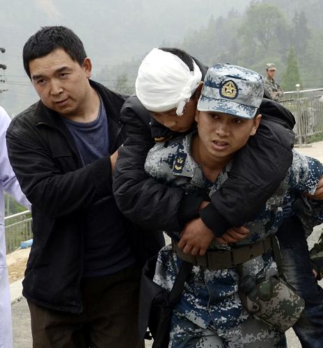4月21日,成都军区空军某通信训练基地官兵将一名重伤员紧急运送到太平中学的直升机机降点。当日8时左右,成空某通信训练基地的60余名官兵携带救灾物资向灾区进发。新华社发(樊尚诚 摄)