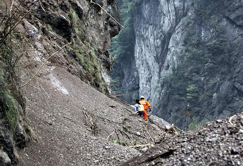 4月21日,在四川省雅安市芦山县地震重灾区宝盛乡,人们冒着余震危险攀越山体滑坡路段。新华社发(张晓理 摄)