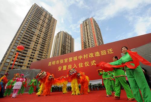 9月28日,昆明市张官营的居民在回迁安置房入住仪式上表演节目,背后的高楼就是他们的新居。当日,云南省昆明市首个“城中村”回迁安置房张官营正式落成入住,500多户村民搬进新居。张官营位于昆明市盘龙区联盟街道办事处,曾经是一个治安问题严重的地区。2008年,昆明市政府开始了张官营“城中村”改造项目,按照“政府主导、企业参与、村民自愿”的工作原则和“先安置、先搬迁、后拆迁”及公益项目先行的运作模式,保证了村民在改造过程中有房可住。如今,新建的回迁安置房占地18.6亩,地上建筑物总面积7.2万平方米,配备了学校、幼儿园及花园、绿地和健身设施等,一个现代化的小区让村民们乐在其中。据了解,今年昆明市的“城中村”改造把回迁安置房建设作为重点,其目标不少于800万平方米。新华社记者 蔺以光 摄
