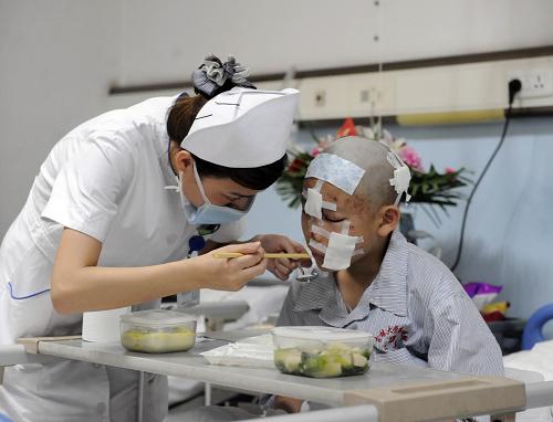 8月16日晚,吉林大学第一医院护士在帮助台湾小伤员进食。新华社记者 林宏 摄