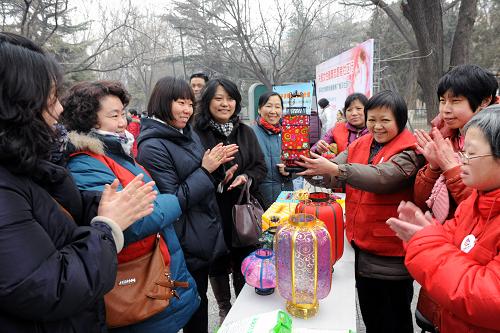 3月1日,受到巾帼志愿者热情关怀的智障人士符志杰(右三)在活动中向来宾展示她制作的灯笼。新华社记者 何俊昌 摄