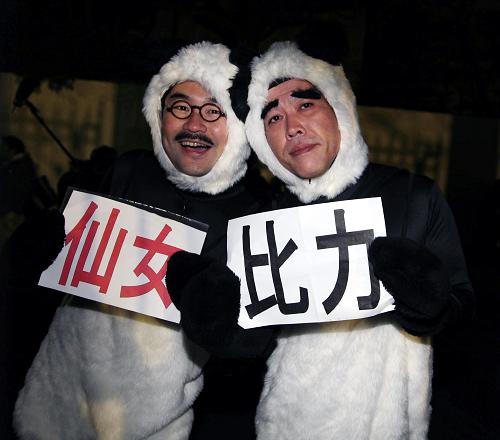 2月21日,在日本东京的上野动物园门口,两名男子身着“熊猫”服装举着“比力”和“仙女”的名字等候中国大熊猫到来。 当日,来自中国四川的大熊猫“比力”和“仙女”抵达日本东京成田机场,当天深夜入住东京上野动物园。这是2008年4月大熊猫“陵陵”因衰老离世以来,大熊猫再一次现身东京。 新华社记者冯武勇摄