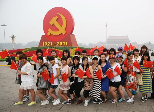 7月1日,一队游客在广场“红心向党”花坛前合影。 当日,来自全国各地的数万名群众汇聚北京天安门广场,观看隆重的升旗仪式,纪念中国共产党成立90周年。 新华社发(李方宇 摄)