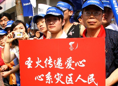 5月23日,群众在火炬传递现场手持“圣火传递爱心 心系灾区人民”标语牌。当日,北京奥运会圣火在上海传递。 新华社记者陈飞摄