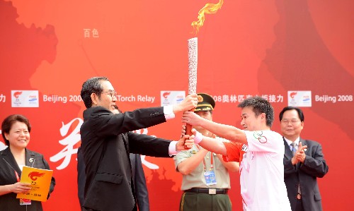 6月6日,广西壮族自治区主席马飚(前左)将火炬交给第一棒火炬手唐灵生。当日,北京奥运圣火在广西桂林传递。 新华社记者 安治平 摄