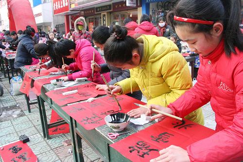 1月26日,安徽省含山县青少年书法爱好者在街头义务书写春联。当日,安徽省含山县60多位青少年书法爱好者走上街头义务为群众书写春联,送上新春祝福。新华社发(程千俊 摄)