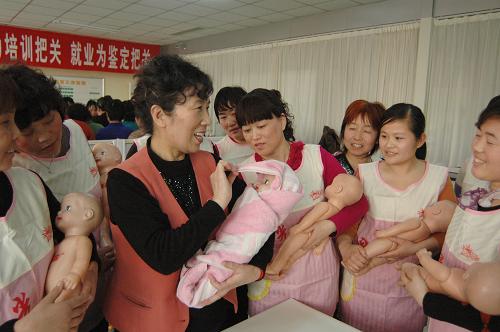 2月21日,在济南阳光大姐家政服务培训中心,来自山东各地的学员在老师(左三)的指导下学习包裹新生儿。新华社发(张振祥摄)