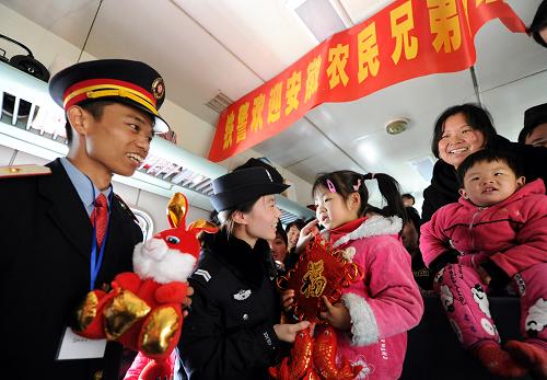 1月21日,L160次列车上,列车长余海堂(左一)和铁警梁梦莹(左二)为旅客们送上新春小礼品。当日,安徽蚌埠铁路公安处组织辖区内民警,从湖北麻城火车站登上东莞东至阜阳的L160次农民工专列,为车上的农民工们送上新春祝福,缓解农民工长时间旅途的疲劳。新华社记者 郭晨 摄