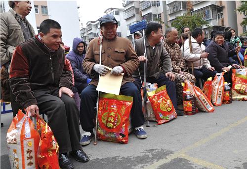 1月21日,广西柳州秀山社区的困难残疾人在春节慰问活动上开心地领取慰问品。新华社发(赖柳生 摄)