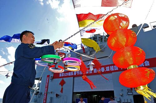 当地时间2月1日,一名中国海军战士在“千岛湖”舰飞行甲板上布置团拜晚会会场。当天,中国海军第七批护航编队“舟山”舰、“徐州”舰、“千岛湖”舰在刚刚完成第291批护航任务后,利用漂泊待机的一天时间,三舰并靠,800名护航官兵首次在护航中相聚,欢庆2011年春节。官兵们每人领到了一份国内捎来的慰问品“年货”,除值更人员外,编队还给每人发一瓶啤酒参加年夜饭聚餐。晚上在“千岛湖”舰的飞行甲板上,举行了别具一格的“大洋春晚”,各舰官兵表演了丰富多彩的文艺节目。2月2日清晨,护航编队再次扬帆起航,执行第292批21艘商船的护送任务,并在三天的护航任务中度过除夕春节。新华社记者 范军威摄