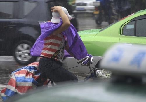 6月11日上午,广东汕头街头,一名居民手护着帽子顶风冒雨艰难骑车出行。 今年第3号热带风暴“莎莉嘉”于6月11日早晨5时45分在广东汕头市濠江区沿海地区登陆,登陆时中心附近最大风力8级。 广东省气象台预计,“莎莉嘉”登陆后继续向偏北方向移动,强度将迅速减弱。受“莎莉嘉”影响,11日粤东沿海和陆地有5至7级大风,汕头、梅州、揭阳、潮州等地市仍有大到暴雨。 新华社发(姚军 摄)