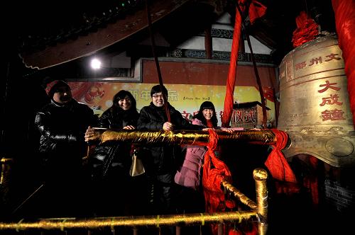 2012年1月1日零时许,市民在郑州文庙大成殿敲钟祈福。 当日,人们在郑州文庙敲响大钟,祈祷新年平安幸福。 新华社记者 朱祥 摄