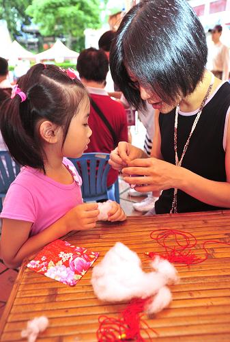 6月23日,在台北市儿童育乐中心,小朋友在大人的协助下制作“香包”。新华社发(吴景腾 摄)