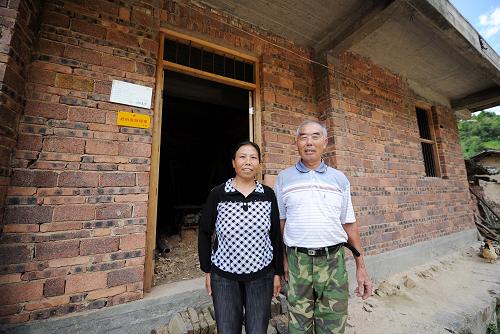 赣州市兴国县枫边乡山阳寨新屋组农民欧阳美萱、黄冬娇夫妇站在政府资助下盖好的新居前(6月30日摄)。 “终于可以住上‘新屋子’嘞!”江西省赣州市兴国县枫边乡山阳寨新屋组农民欧阳美萱将告别有着200多年历史的土坯房,搬进新居。他带着记者参观政府补贴新建的砖瓦房,欢喜得合不拢嘴。欧阳美萱家是山阳寨第一户享受政府援建补贴的农民。 为加大对赣南苏区农村土坯房改造的扶持力度,日前出台的《国务院关于支持赣南等原中央苏区振兴发展的若干意见》提出,到2015年,赣南等原中央苏区在解决突出的民生问题上取得突破性进展,尽快完成赣州市农村危旧土坯房改造任务。 80年前,山阳寨曾是中央苏区红军医院第二分院第四所驻地。在第一次和第三次反围剿中,淳朴的老乡腾出屋子,收治伤员,最多时每户收治伤员10多人。然而由于人均耕地少,地理位置偏,发展滞后,当前群众生活依然贫困,58户居民中仍有56户居住在有一两百年历史的土坯房内。统计显示,截至2011年底,赣州18个县(市、区)仍有60多万户农民居住在土坯房里,占农村总户数的40.6%。 据了解,为支持赣州土坯房改造,中央财政将在原来农