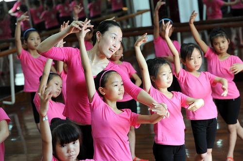 6月29日,余姚市青少年宫的舞蹈老师在教农民工子女学习舞蹈动作。 6月26日,由浙江余姚市青少年宫举办的首期新小公民“红舞鞋”夏令营开班,来自贵州、安徽、四川、湖南等地的20名8至12岁农民工子女参加这次免费舞蹈培训。 新小公民“红舞鞋”夏令营是余姚市青少年宫暑期免费开放公益活动系列之一,旨在帮助更多渴望得到艺术培养的农民工子女实现梦想。 新华社发(陈斌荣 摄)