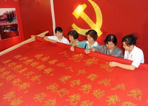 6月26日,几名参观展览的党员在工作人员帮助下绣“入党誓词”。新华社记者 罗晓光 摄