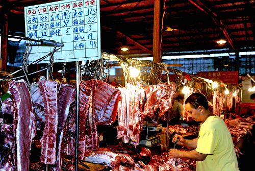 7月14日,一位猪肉零售商在福州市一农贸市场整理自己的肉铺迎候顾客。新华社记者张国俊 摄