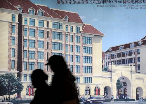 9月24日,两位市民从一幅楼盘的广告宣传画前走过。新华社记者 蔺以光 摄
