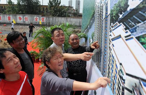 9月28日,在开工仪式现场,搬迁群众潘雪兰(中)等在观看项目建成后的效果图。新华社发(解琛 摄)