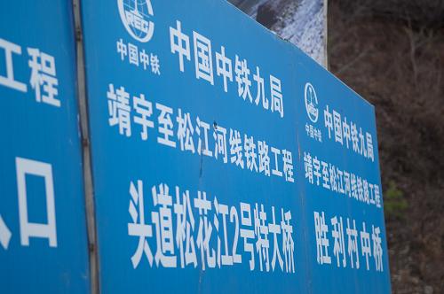 被指偷工减料投入碎石的2号特大桥工程牌(10月21日摄)。近日,吉林省白山市的靖宇县和抚松县境内一段总价值23亿元的铁路工程被指违规分包给一家“冒牌”公司和几个“完全不懂建桥”的包工头,本应浇筑混凝土的桥墩,竟在工程监理的眼皮底下,被偷工减料投入大量石块,形成巨大的安全隐患。当记者21日来到“靖宇至松江河线工程”铁路工程现场,十几根50米高的桥墩矗立在头道松花江湖畔,现场已看不到任何施工人员。中铁九局副局长赵铁军向记者表示,中铁九局已就此成立专门调查组,将对相关桥墩进行钻芯取样,绝不容许存在工程质量问题;对于暴露出的管理缺失,则应充分总结教训,避免再次出现此类问题。“靖宇至松江河线工程”位于吉林省白山市的靖宇县和抚松县境内,线路全长74.1公里,2009年由铁道部批准建设,项目业主单位为沈阳铁路局。新华社记者 许畅 摄