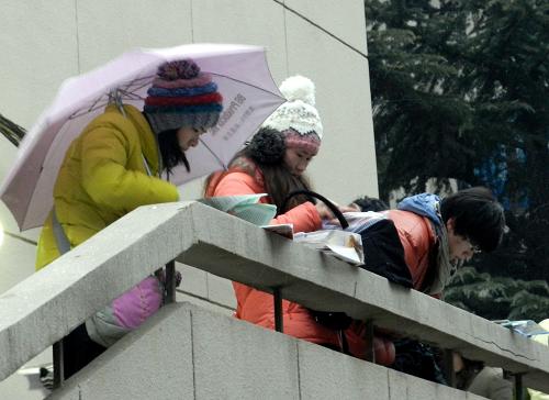 1月7日,考生在北京清华大学考点考场外打着伞冒雪“临阵磨枪”。新华社发 (王振 摄)