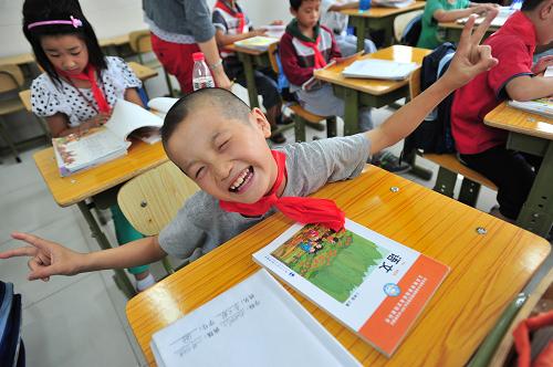 2011年9月1日,北京石油学院附属小学北校区的一名二年级学生在拿到新教材后十分高兴。北京石油学院附属小学北校区是海淀区东升学区一所重点安置打工子弟小学学生的公办学校,该校共计安置打工子弟小学学生876人。新华社发(崔楠 摄)