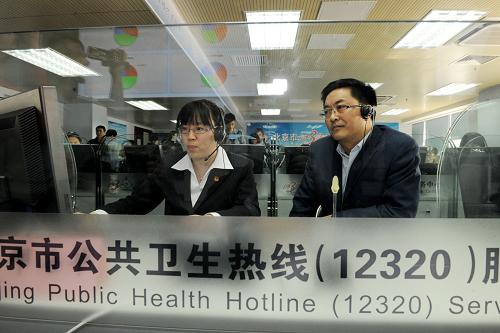 3月20日,卫生部新闻发言人邓海华(前右)和“12320”卫生热线坐席员一起接听热线。新华社记者 何俊昌 摄