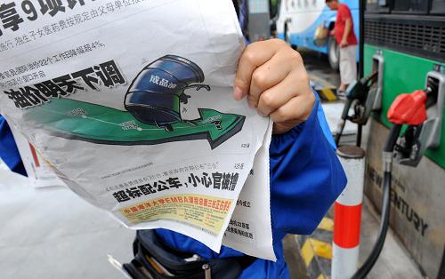 7月10日,青岛一加油站员工在工作间歇翻看报纸。近日,国家发改委表示,7月11日成品油调价窗口将开启,国内油价将再次下调。这将是现行成品油价格形成机制实施以来我国成品油价格首次“三连跌”。据预测,此次跌幅可能会在350元至400元/吨左右。新华社记者 李紫恒 摄