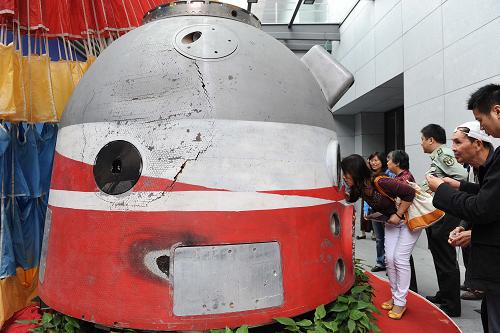 10月27日,在“圆梦九天——中国载人航天工程的壮丽航程”展览上,参观者在观看神舟四号飞船返回舱。新华社发(赖鑫琳 摄)