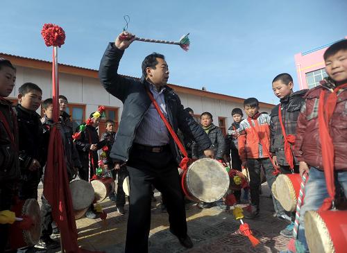12月25日,兰州市皋兰县西岔中心小学乡村学校少年宫辅导员郭旭东(前)在指导小学员打太平鼓。近年来,兰州市着力解决城乡学生课外教育阵地失衡问题,探索在农村地区建设乡村学校少年宫,以丰富农村学生课外教育,目前已经建成乡村学校少年宫43个。乡村学校少年宫立足乡村文化教育实际,开设太平鼓、秦腔、皮影等非物质文化遗产兴趣班,受到学生的欢迎。新华社记者 聂建江 摄