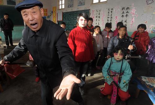 12月25日,兰州市皋兰县秦腔艺人保承明(前左一)在指导西岔中心小学乡村学校少年宫学员唱秦腔。新华社记者 聂建江 摄