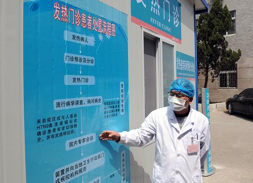 4月14日,河南省开封市河南大学淮河医院工作人员介绍发热门诊患者处置流程图。新华社记者 李博 摄