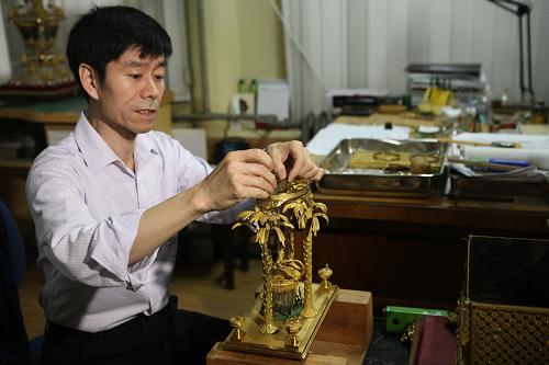 6月8日,故宫钟表修复专家王津在工作室内修复受损的清代铜镀金转花水法人打钟。新华社发(刘长龙 摄)