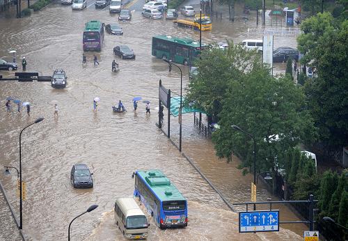 10月8日,积水漫过杭州市学院路和天目山路路口。部分车辆在水中抛锚,行人被迫涉水前行。由于台风“菲特”影响逐渐减弱,杭州市气象台当日14时20分解除暴雨橙色预警。但是连续两天的强降雨已导致杭州十多处道路路段积水,部分地区交通受阻,给市民出行和生活带来较大影响。新华社记者 鞠焕宗 摄