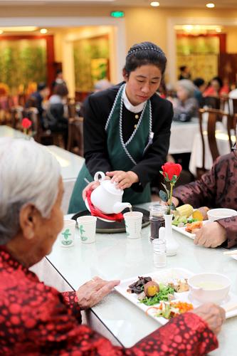 10月13日,金手杖公寓工作人员为老年人节日聚餐服务。 重阳节来临之际,北京市昌平区郑各庄村70岁以上老年人免费入住村办水城金手杖国际养生公寓养老。该村近年来发展集体经济,建立郑各庄村老年慈善专项基金,自筹资金创办了金手杖养生公寓。它集社区养老、医疗养老、机构养老、度假养老等优势于一身,建立了多元化、分层次的综合养老网络,满足现阶段不同家庭照顾老年人的不同需求。 新华社发(朱树堂 摄)