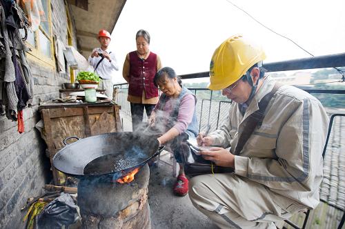 10月15日,国网重庆永川供电公司的一名电力职工在“弃管小区”之一的永川火车站南路48号的老旧居民楼内了解收集当地住户在电力设施设备改造的需求。新华社记者 刘潺 摄