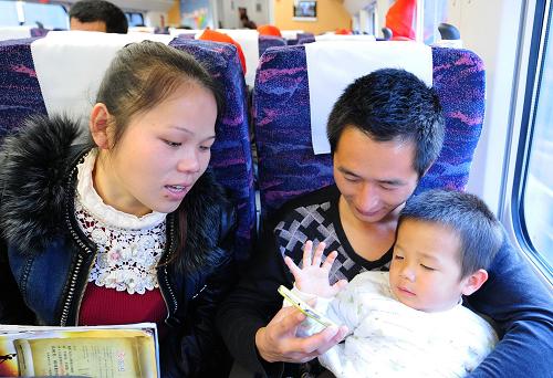 1月24日,齐平华、章元妹(左)夫妇和他们的大儿子齐志杰在D6502次新福州人免费返乡动车专列上。当日,中铁四局福州京台高速JTA6合同段工人齐平华、章元妹夫妇带着大儿子一同乘坐福州开往南昌的D6502次“新福州人免费返乡动车专列”,踏上回家过年的旅程。下午,他们回到了老家江西省进贤县泉岭乡大塘村,和家人在小年这天团聚。“回家过年”是齐平华夫妇这样外出打工者过年时的祈盼。齐平华说:“去年回家还要等加增的临客车,今年能坐上新福州人免费返乡动车专列,又快又方便。”新华社记者 林善传 摄