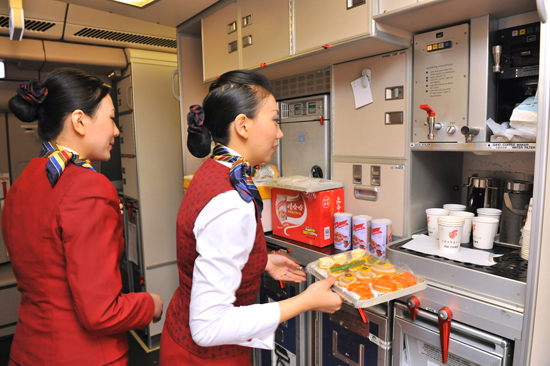 2月23日,在负责撤回利比亚中方人员的首架中国国航A330包机上,空中乘务员正在准备餐食。新华社发(王泽民 摄)
