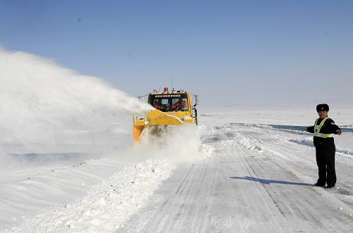 3月17日,机械手驾驶清雪机械在国道217线新疆阿勒泰段清除积雪,交警在一旁指挥过往车辆。新华社发(叶尔江 摄)