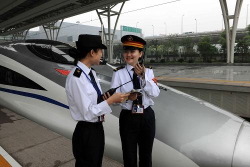 6月17日,CRH380高速动车刚刚停靠在上海虹桥火车站,车站值班员史洁敏(右)与列车工作人员进行站车交接工作。新华社记者 陈树根 摄