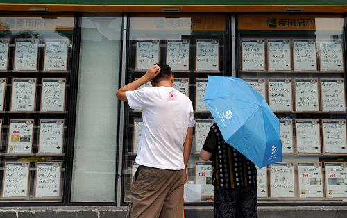 8月26日,两名行人在北京朝阳区一处房屋中介公司外观看二手房信息。新华社记者 罗晓光 摄